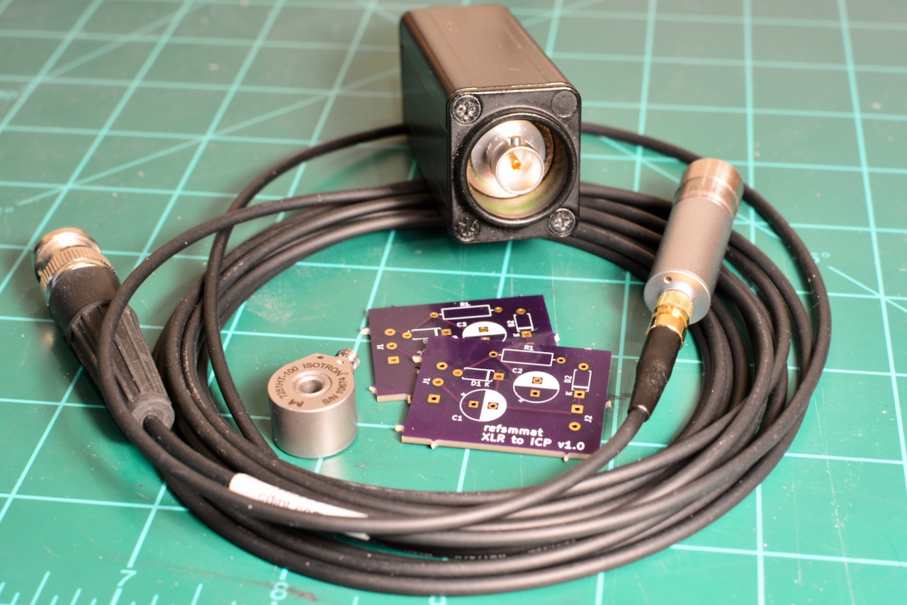 The assembled adapter with spare PCBs, an Endevco 7251HT accelerometer, and a coaxial cable connected to a Bruel & Kjaer 4188 microphone on a 2695 CCLD preamplifier.