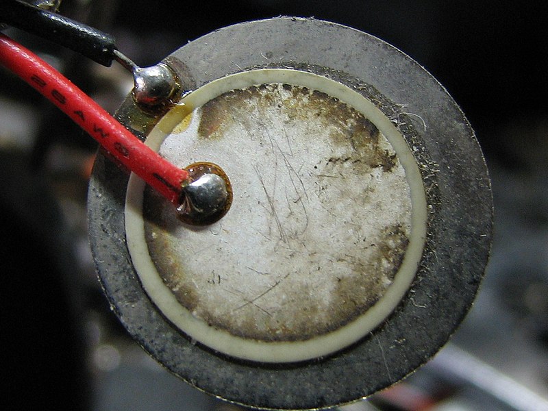 A piezoelectric disk buzzer, such as you might turn into a DIY contact microphone. Photo by Gophi, CC BY-SA 3.0, via Wikimedia Commons.